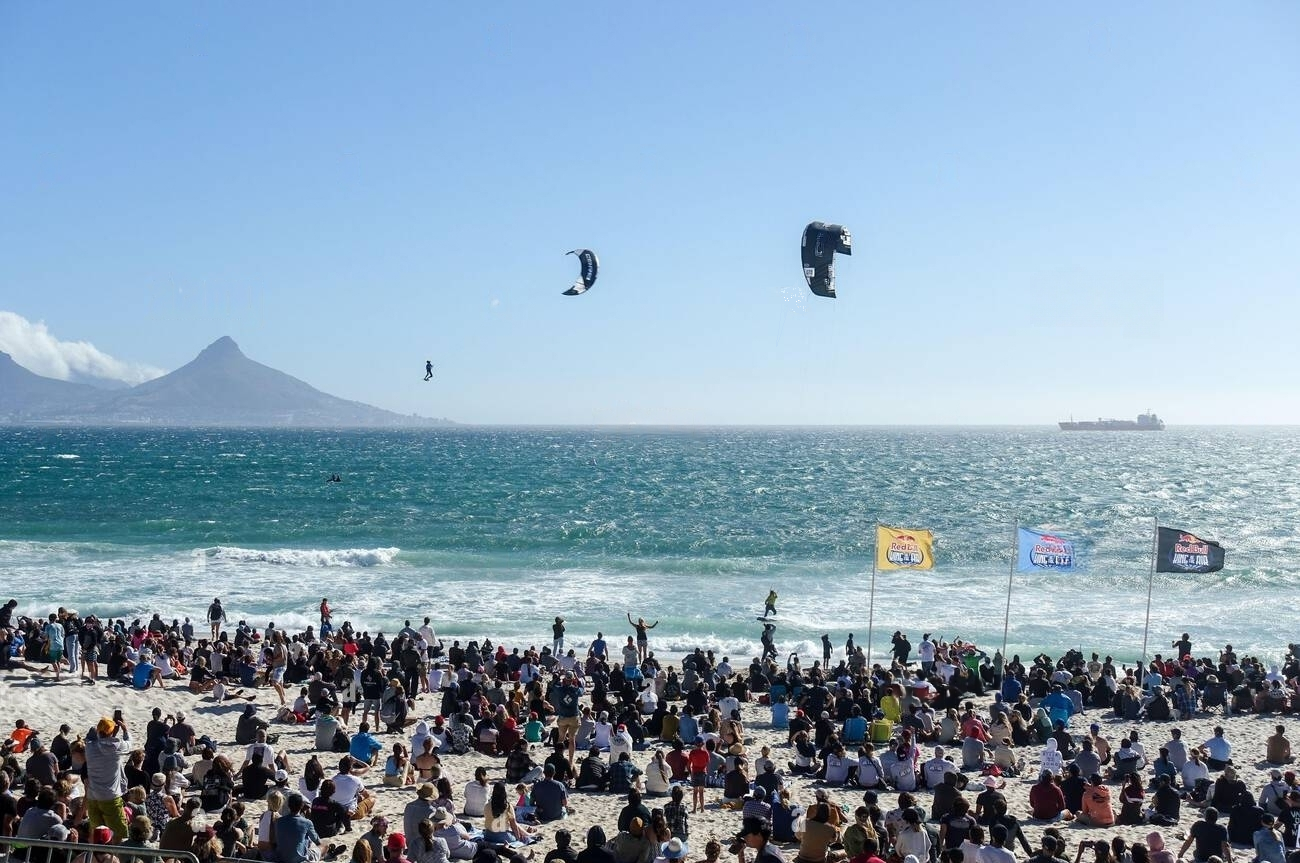 crowd-of-visitors-watching-kitesurfers-competing-at-the-red-bull-king-of-the-air-2021-in-blouberg-cape-town-south-africa-2HB6AM5-transformed crowd on bloubergstrand beach watching kitesurfing