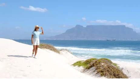 woman walking on bloubergstrand beach with table mountain in background